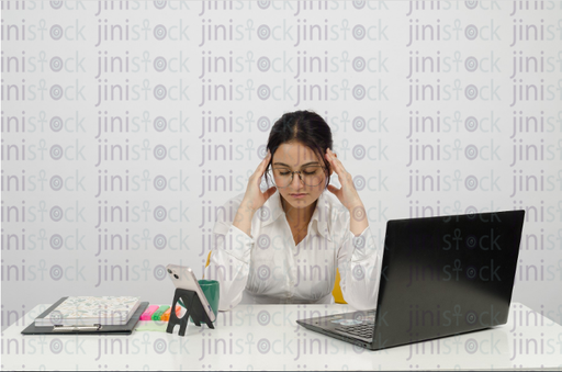 A woman is working on a laptop and has a headache - stock image