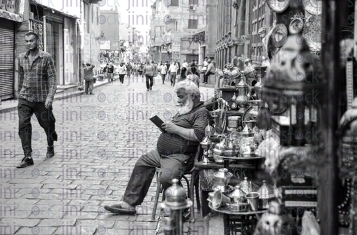 old man reading in the street - stock image