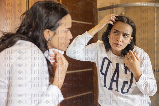 woman checking her face for wrinkles in the bathroom mirror