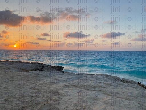 sea sunt set on a rocky beach - stock image