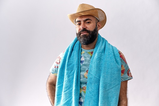 man with beard wearing  hat and carrying his towel over his shoulders.