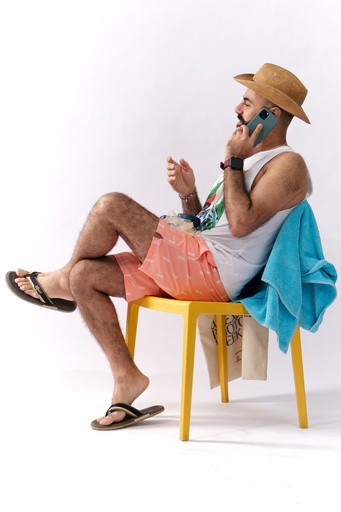 man talking on the phone while sitting under the sun.