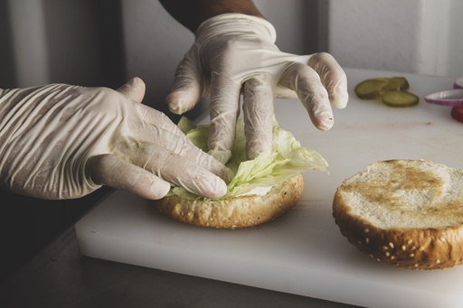 Chef adding lettuce to bread bun