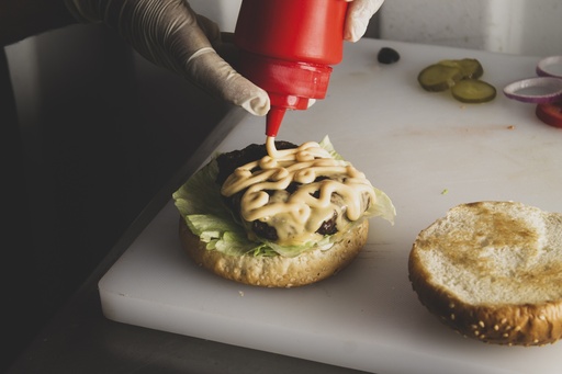 Close up on hands adding sauce to the burger