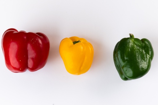 green, yellow and red coloured pepper on white background