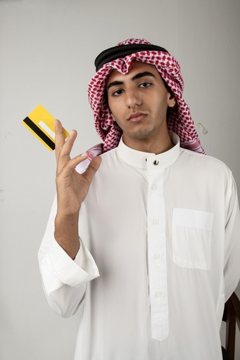 A young Gulf man holding a Visa card