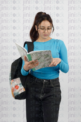 Girl wearing glasses reading a book - holding a backpack - close-up front portrait - stock image