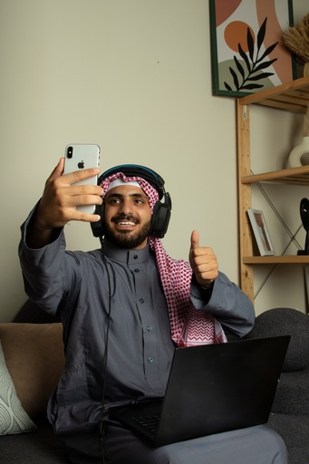 A young Gulf man is having a video chat on his iPhone and is happy