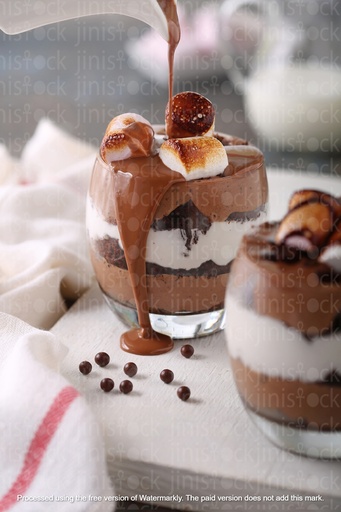 Chocolate dessert with marshmallows, layered in a glass, topped with a drizzle of melted chocolate.