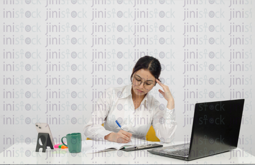 Woman sitting at a desk - writing - laptop in front of her - cup of coffee - close-up front shot - stock image