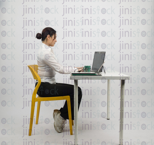 Woman sitting at desk - typing on laptop - close-up side shot - stock image