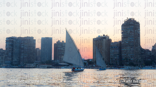 A boat in the Nile with a white sail at sunset