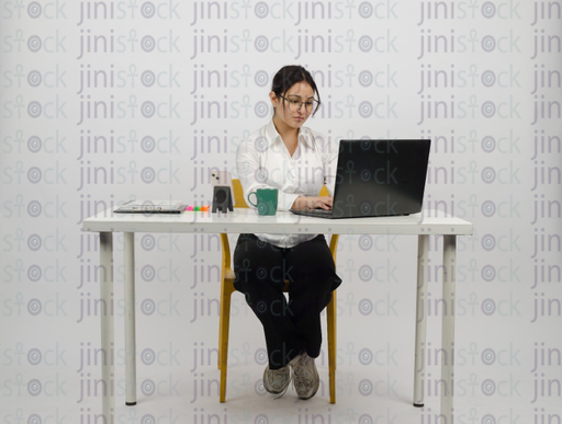 [NA0057] Woman sitting at desk - working on laptop - cup of coffee in front of her - close front shot - stock image