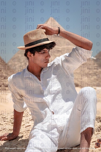 young man adjusting his hat infront of the pyramids