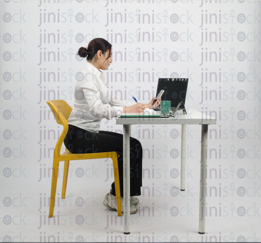 Woman sitting at desk, writing and looking at mobile - close-up side shot - stock image