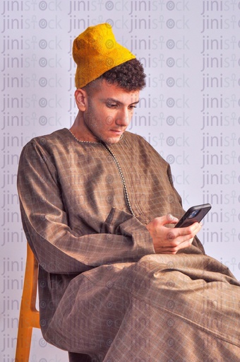 Egyptian farmer sitting and texting on the mobile phone