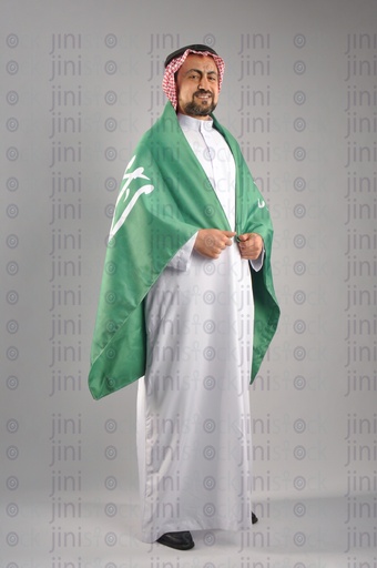 Saudi Arabian man smiling and wearing the Saudi Arabian flag to celebrate the Saudi founding day.