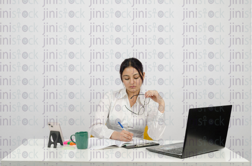 Woman writing and holding glasses in her hand - close-up - stock image