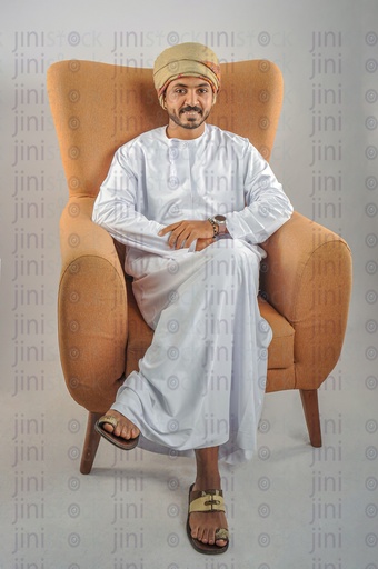 An Omani man wearing the Omani clothes sitting on a chair