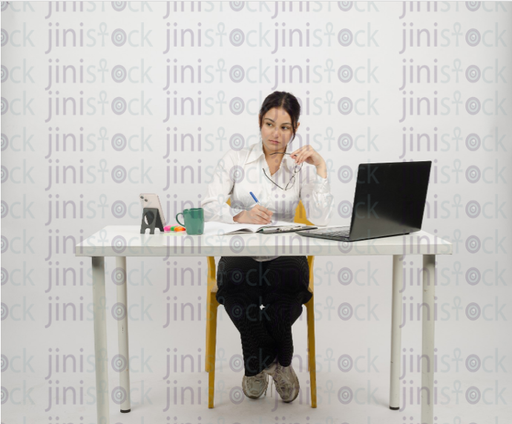 Woman sitting at desk - writing - thinking - glasses in hand and looking to the side - close-up front shot - stock image