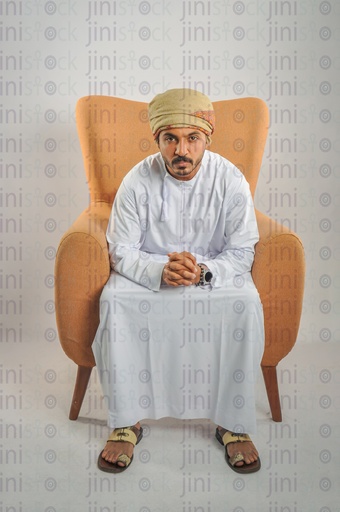 An Omani man from the Gulf wearing Omani clothes sitting on a chair