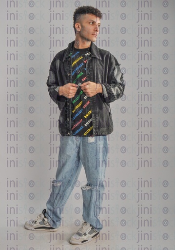 A cool Egyptian young man wearing trousers and a jeans jacket and holding his jacket.