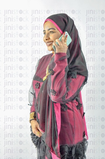 A Nubian Egyptian woman wearing Nubian clothes, putting a veil on her hair, and talking on the mobile phone