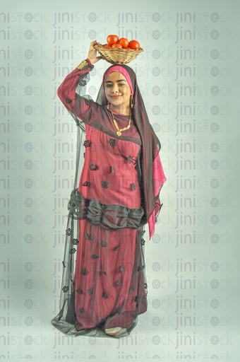A Nubian woman from Egypt wearing Nubian clothes and putting a plate of tomatoes on her head.