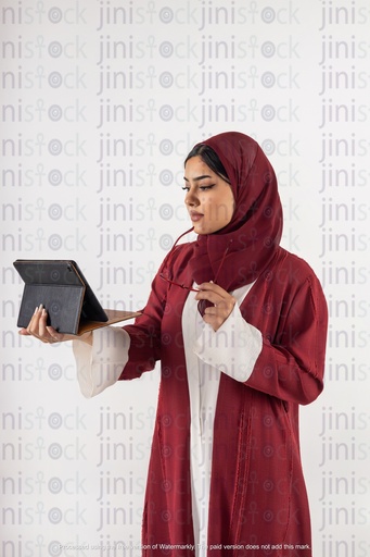 امرأة سعودية خليجية تعمل وتنظر إلى جهاز الآيباد