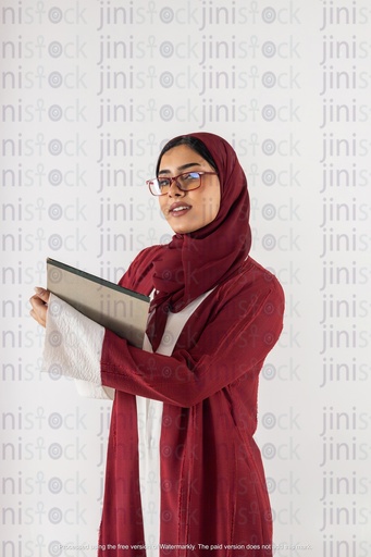 سعودي خليجي يعمل من الخليج يحمل دفتر ملاحظات وينظر إلى الكاميرا