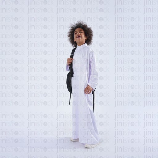 صبي خليجي سعودي واقف يحمل حقيبة مدرسته سعيدًا يضحك