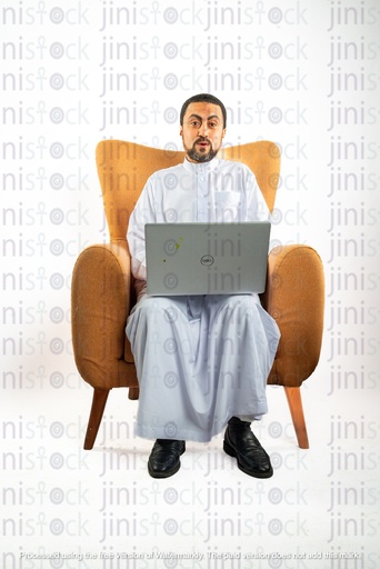 saudi khaliji man from gulf sitting on a chair working on his laptop and surprised