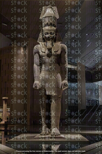 An Egyptian girl stands in front of the statue of Ramses II inside an Egyptian museum.