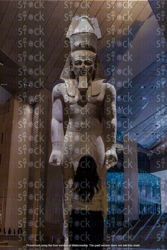 An Egyptian girl stands in front of the statue of Ramses II inside an Egyptian museum.
