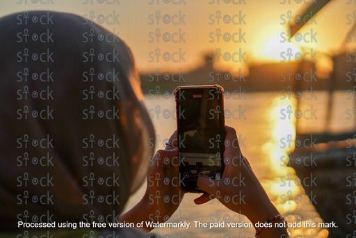 فتاة تصور بالهاتف منظر غروب الشمس مع فلوكة في النيل