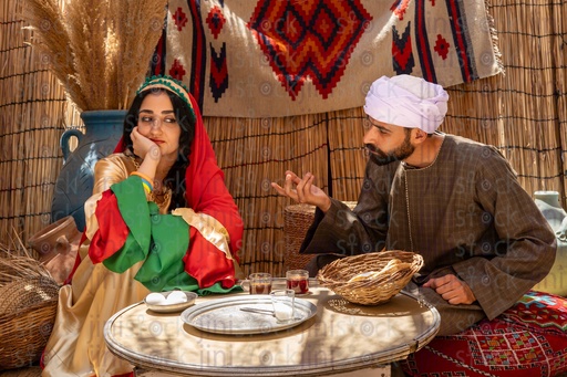 An Egyptian farmer talking to his wife while sitting on a tray 
