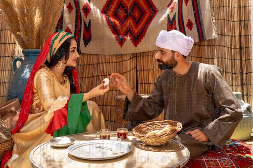 An Egyptian farmer having breakfast with his wife sitting on a tray drinking tea 