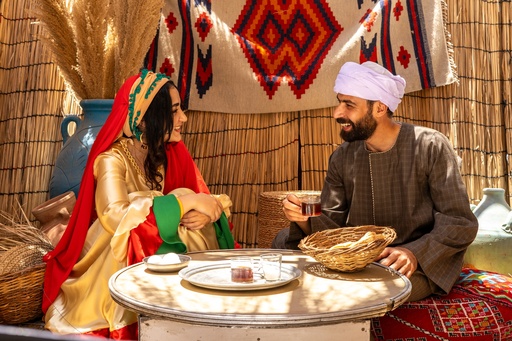 Egyptian man sitting on a tray with a girl in a beautiful peasant costume 