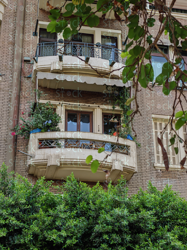 عمارة قديمة تتزين بلكونات حديد مشغول والزرع متدلي