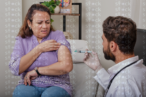 المريضة تمسك ذراعها بألم اثناء اخذ الحقنه