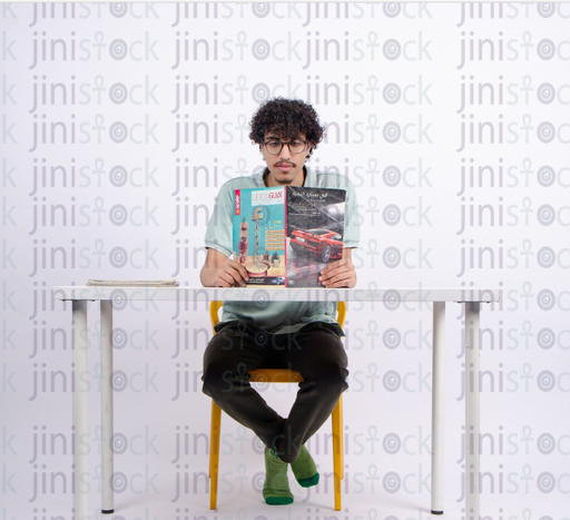 a young man reading in a book while sitting on his office - stock image