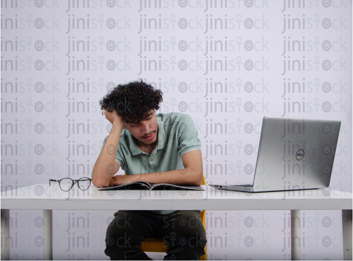 young man with curly hair sleeping while studying - stock image